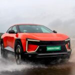 Mahindra BE 6 electric SUV driving on wet road in rain